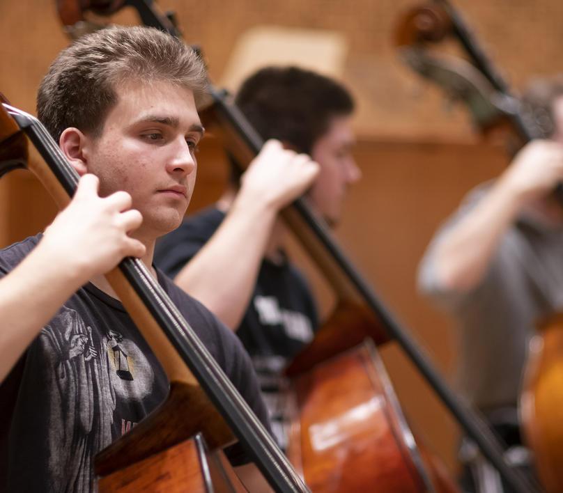 Students in an orchestra rehearsal with John Adams