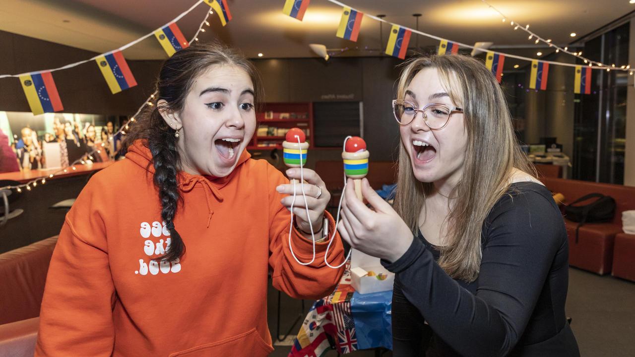 Two individuals have an excited expression as they play the classic cup-and-ball game