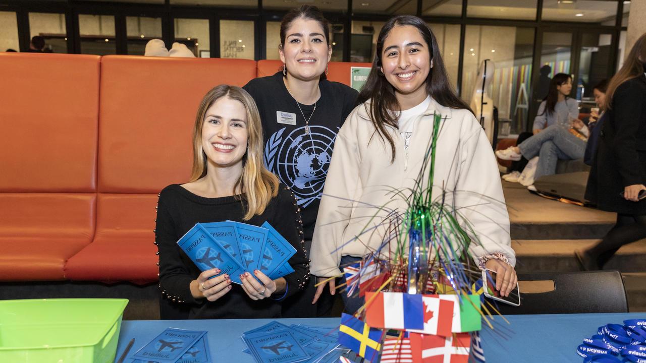 Three people at a welcome table in the lobby distribute paper "passports" for the international festivities